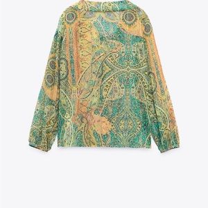 Shirt w adjustable self tie Vneckline wood trim. Long sleeve w buttoned cuffs.